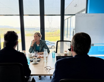 Cécile Neven est assise face à  François Lepot  et Olivier Servais dans une salle de conférence.