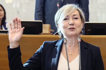 Cécile Neven, souriante, lève la main droite durant sa prestation de serment dans la salle des Séances plénières au Parlement wallon.